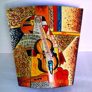 May include: Abstract art piece featuring a violin. The artwork uses a vibrant palette of orange, yellow, red, and black. The violin is central, with musical notes and geometric shapes. The piece has a textured, painted appearance.