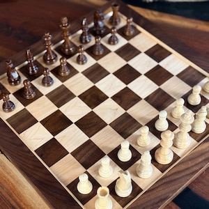 May include: A wooden chessboard featuring a grid of alternating dark walnut and light maple squares. The board is set with a complete collection of carved wooden chess pieces, with dark brown pieces on one side and light cream pieces on the other.