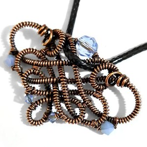 May include: A copper-colored wire-wrapped pendant necklace with a black cord. The pendant features an abstract design with multiple loops and is adorned with light blue crystal beads. The necklace is displayed against a white background.