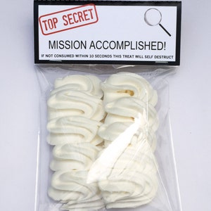 May include: A clear plastic bag containing several white, swirled treats. The bag has a black and white label that reads "TOP SECRET" and "MISSION ACCOMPLISHED!" with the warning "IF NOT CONSUMED WITHIN 10 SECONDS THIS TREAT WILL SELF DESTRUCT."