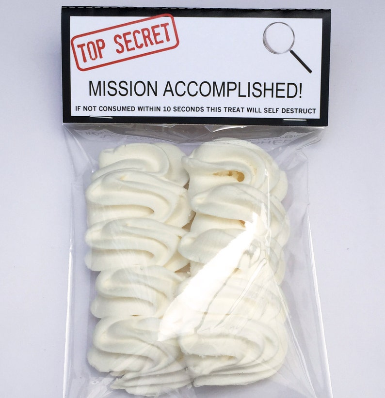 May include: A clear plastic bag containing several white, swirled treats. The bag has a black and white label that reads "TOP SECRET" and "MISSION ACCOMPLISHED!" with the warning "IF NOT CONSUMED WITHIN 10 SECONDS THIS TREAT WILL SELF DESTRUCT."