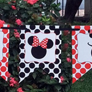 May include: A red and white polka dot banner with the letters "OUR" and a black and white image of Minnie Mouse. The banner also has the text "NEXT" on it.