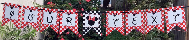 May include: A red and white polka dot banner with the letters "OUR" and a black and white image of Minnie Mouse. The banner also has the text "NEXT" on it.