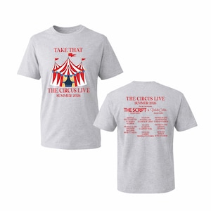 May include: A grey t-shirt with a circus tent graphic in red, white, and blue, and the text "TAKE THAT THE CIRCUS LIVE SUMMER 2026". The back displays tour dates and "THE SCRIPT & Blind C." in red.
