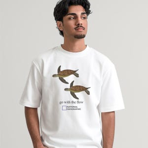Camiseta unisex de estilo vintage con estampado de tortuga marina "Go With The Flow" (Déjate llevar por la corriente). 100% algodón. Regalo original.