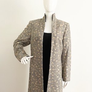 May include: A long, gray coat with a mandarin collar and a floral pattern in a lighter shade of gray.