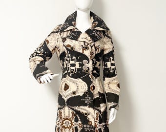 May include: A vintage knee-length coat with a striking black, cream, and brown geometric design. The coat has a double-breasted closure, wide lapels, and long sleeves. The coat is displayed on a mannequin.