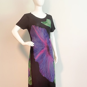 May include: A black maxi dress with a large purple and pink flower print. The dress has short sleeves and a round neckline.