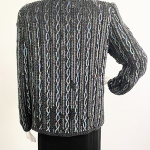 May include: A black sequined cardigan with a chain-link pattern. The sequins have an iridescent finish.