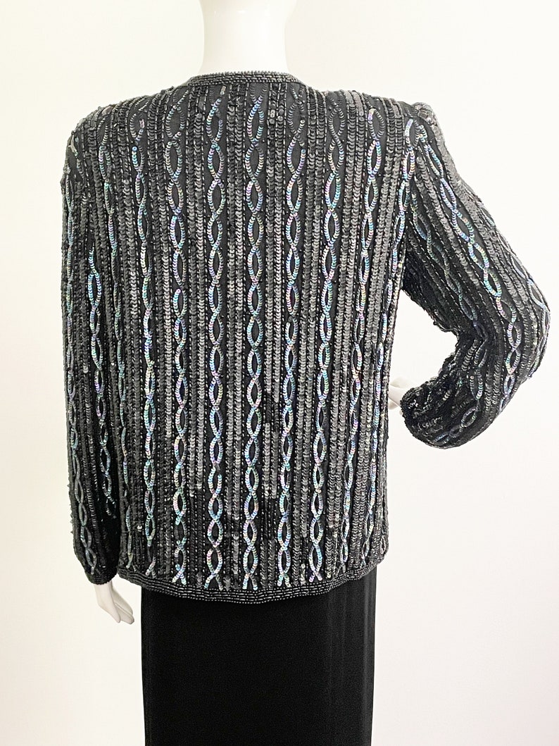May include: A black sequined cardigan with a chain-link pattern. The sequins have an iridescent finish.