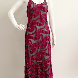 May include: A long, black and magenta dress with a swirling pattern. The dress is made of a sheer fabric with a velvet overlay.