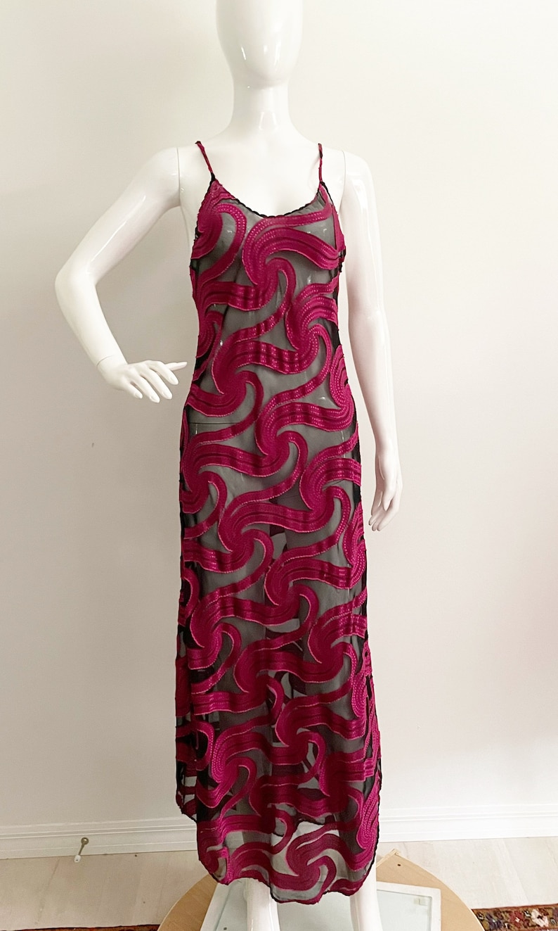 May include: A long, black and magenta dress with a swirling pattern. The dress is made of a sheer fabric with a velvet overlay.