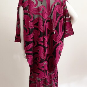 May include: A long, black and magenta dress with a flowing, abstract pattern. The dress is made of a sheer fabric with a delicate, embroidered design.