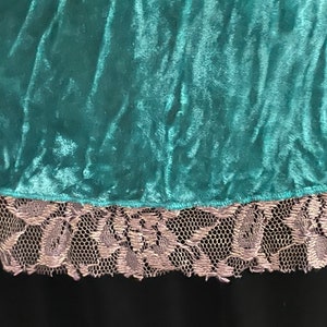 May include: Teal velvet fabric with a silver lace trim. The fabric has a soft, plush texture.