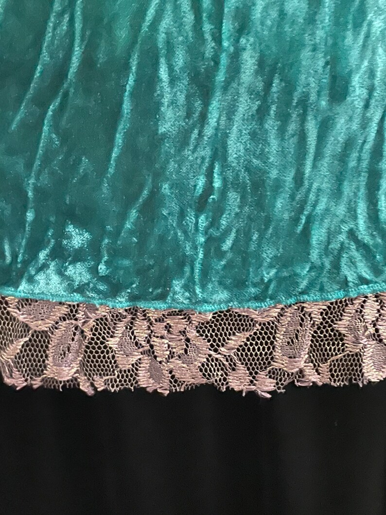 May include: Teal velvet fabric with a silver lace trim. The fabric has a soft, plush texture.