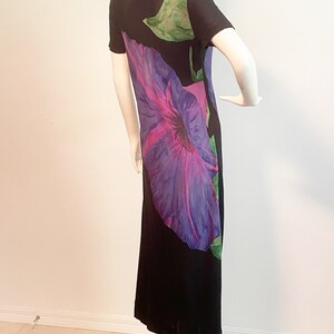 May include: A black maxi dress with a large purple and pink flower print. The dress has short sleeves and a scoop neck.