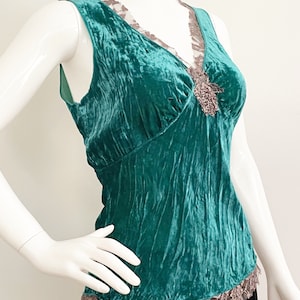 May include: Teal blue velvet sleeveless top with a lace trim and a beaded embellishment at the neckline.