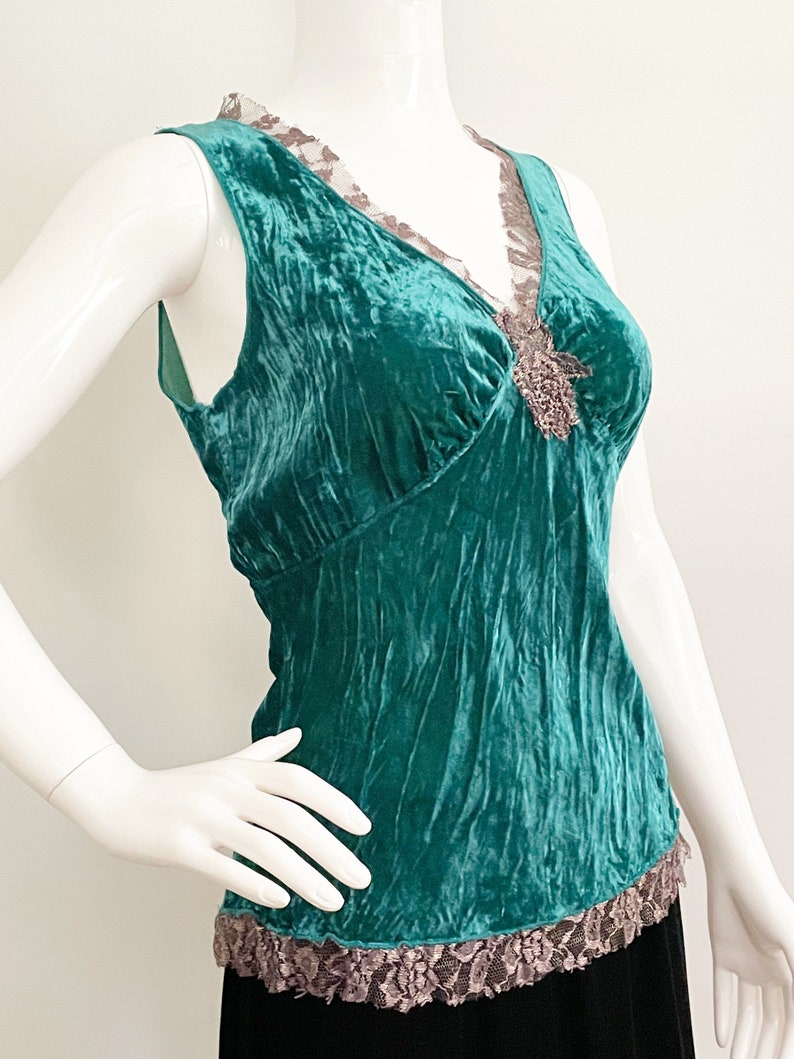 May include: Teal blue velvet sleeveless top with a lace trim and a beaded embellishment at the neckline.