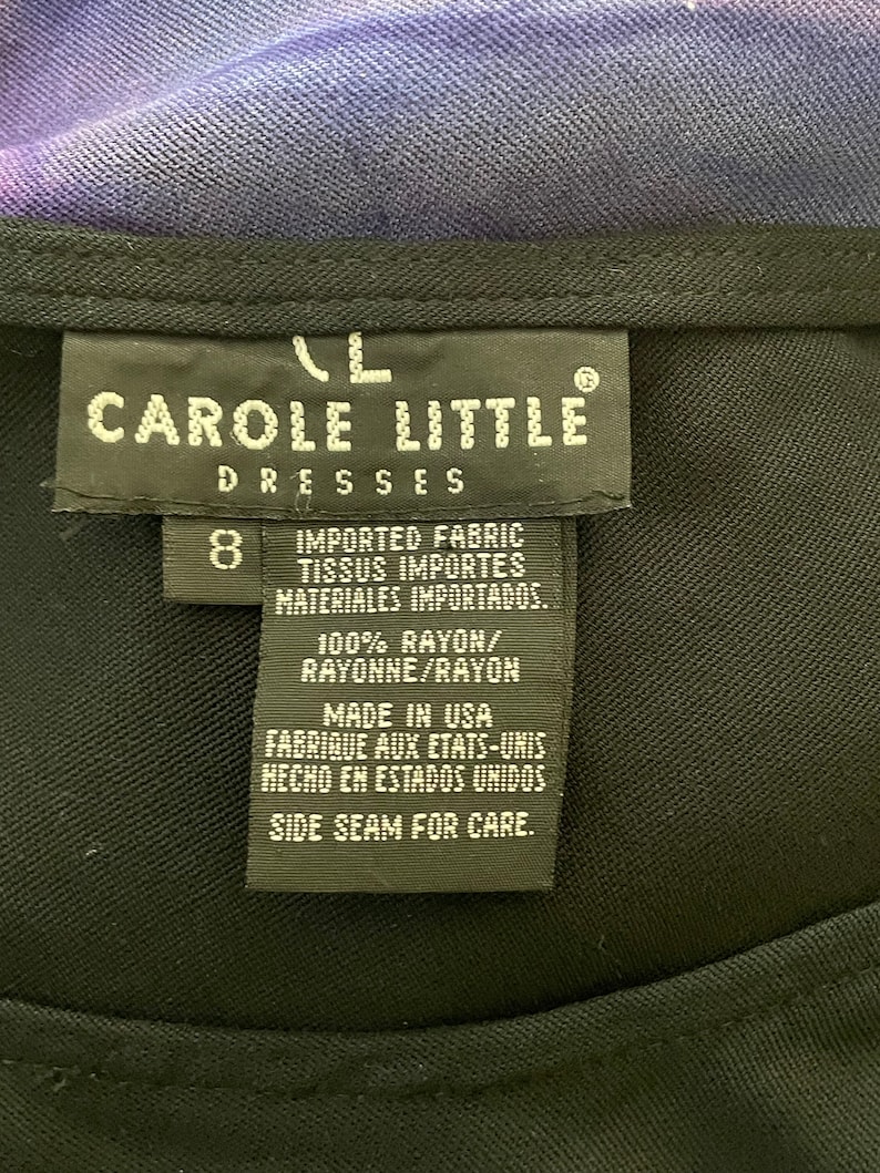 May include: A black tag with white text that reads "Carole Little Dresses" and "Imported Fabric, Tissus Importes, Materiales Importados." The tag also says "100% Rayon/Rayonne/Rayon", "Made in USA, Fabrique aux Etats-Unis, Hecho en Estados Unidos", and "Side Seam for Care."