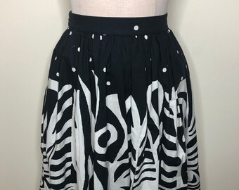 May include: A black and white patterned skirt with a full, gathered silhouette. The skirt has a black waistband and a white trim at the hem.