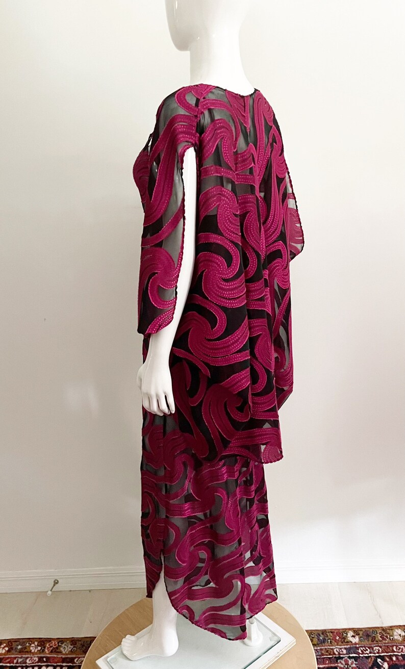 May include: A long, black and magenta dress with a swirling pattern. The dress is made of a sheer fabric with a velvet overlay.