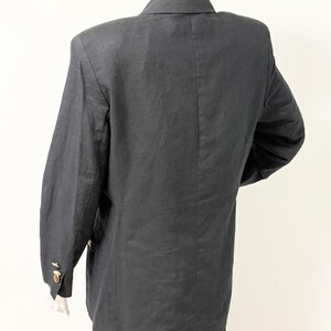 Puede incluir: Un blazer gris oscuro con botones dorados, exhibido en un maniqu&iacute;. El blazer tiene mangas largas y un cuello cl&aacute;sico. La tela parece ser lino o una mezcla de lino. El blazer es de estilo cl&aacute;sico.