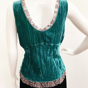 May include: Teal blue velvet tank top with a lace trim around the neckline and hem.