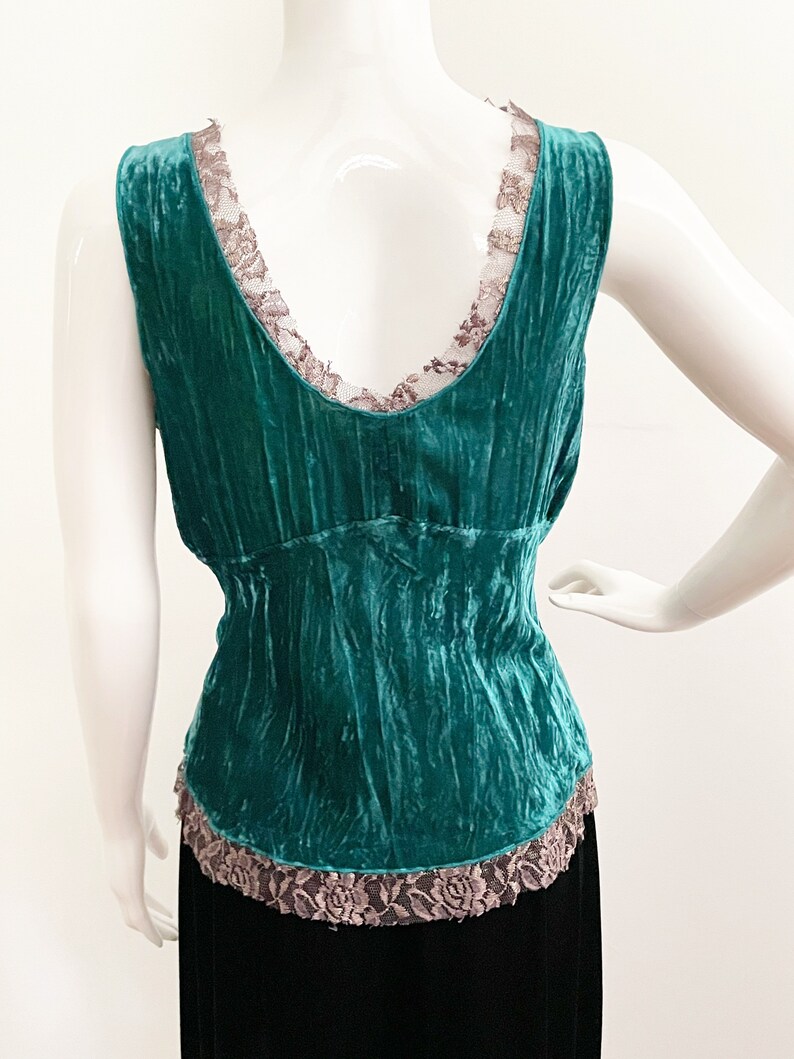 May include: Teal blue velvet tank top with a lace trim around the neckline and hem.