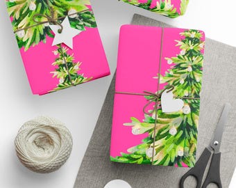 May include: Bright pink gift wrap with a watercolor Christmas tree design. The gifts are tied with twine and adorned with white star-shaped tags. A spool of twine, scissors, and blank tags are also visible.