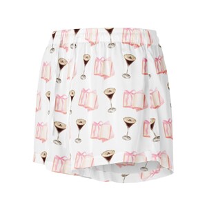 May include: White shorts with an all-over pattern of watercolor-style espresso martinis and pink gift boxes tied with pink ribbons. The shorts have an elastic waistband.