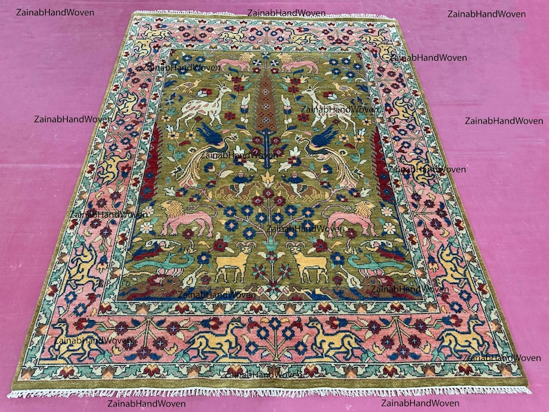 May include: Hand-woven rug with an intricate design featuring deer, birds, and floral motifs in shades of green, pink, blue, and yellow. The rug has a detailed border and a central medallion, showcasing traditional craftsmanship.