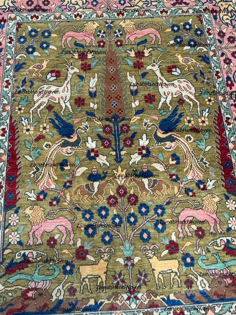 May include: An intricately designed rug with a central olive green field, featuring stylized animals, birds, and floral motifs in pink, blue, and brown. The rug has a detailed border with a pink and red pattern, showcasing a traditional design.