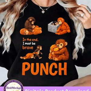 May include: Black sweatshirt with four monkey illustrations. Text reads "In the end, I must be brave" above the orange word "PUNCH". The design includes a digital product download logo. The design is by Samira El Hassani.
