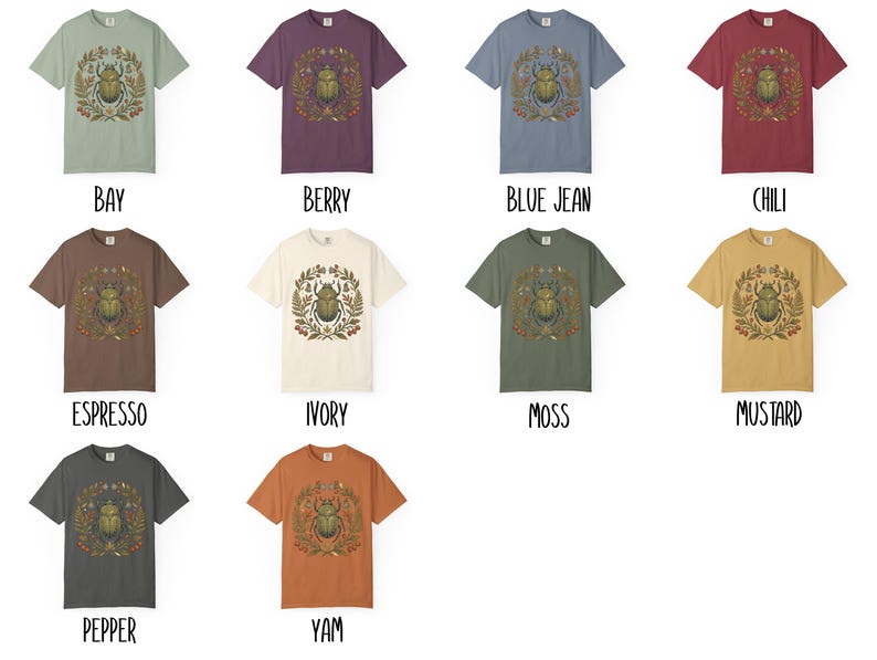 K&ouml;nnte beinhalten: Eine Auswahl an kurz&auml;rmeligen T-Shirts in verschiedenen Farben, jedes mit einer zentralen Grafik eines Skarab&auml;us-K&auml;fers, der von einem botanischen Kranz umgeben ist. Die Shirts sind in Farbt&ouml;nen wie Bay, Berry, Blue Jean, Chili, Espresso, Ivory, Moss, Mustard, Pepper und Yam erh&auml;ltlich.