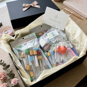 May include: A white ceramic mug with a black handle and the text "But First, Coffee" in a black, bold font. The mug is on a white surface. The mug is likely 11 ounces.