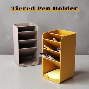 Könnte beinhalten: Zwei mehrstufige Stifthalter sind abgebildet. Einer ist hellbraun, der andere gelb. Der gelbe Stifthalter enthält Stifte und einen Haftnotizblock. Der Text "Tiered Pen Holder" befindet sich über den Stifthaltern.
