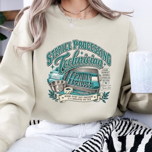 May include: A sand-colored crewneck sweatshirt featuring a graphic print that reads Sterile Processing Technician. The design includes illustrations of medical instruments, a tray, and text stating Clean, Disinfect, Assemble, Sterilize, Deliver.
