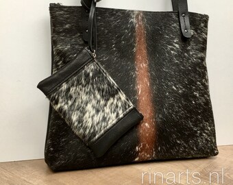 black leather tote with beautiful cow hair front. Black work bag with leopard cow hair. Includes a small zipper pouch.