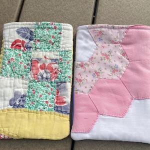 May include: Two handmade quilted items. One features a patchwork design with floral and geometric patterns in red, blue, and green. The other has a pink and floral hexagon pattern. Both have a vintage aesthetic.