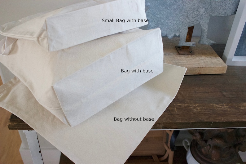 May include: Three white canvas tote bags stacked on top of each other. The top bag is labeled "Small Bag with base", the middle bag is labeled "Bag with base", and the bottom bag is labeled "Bag without base".