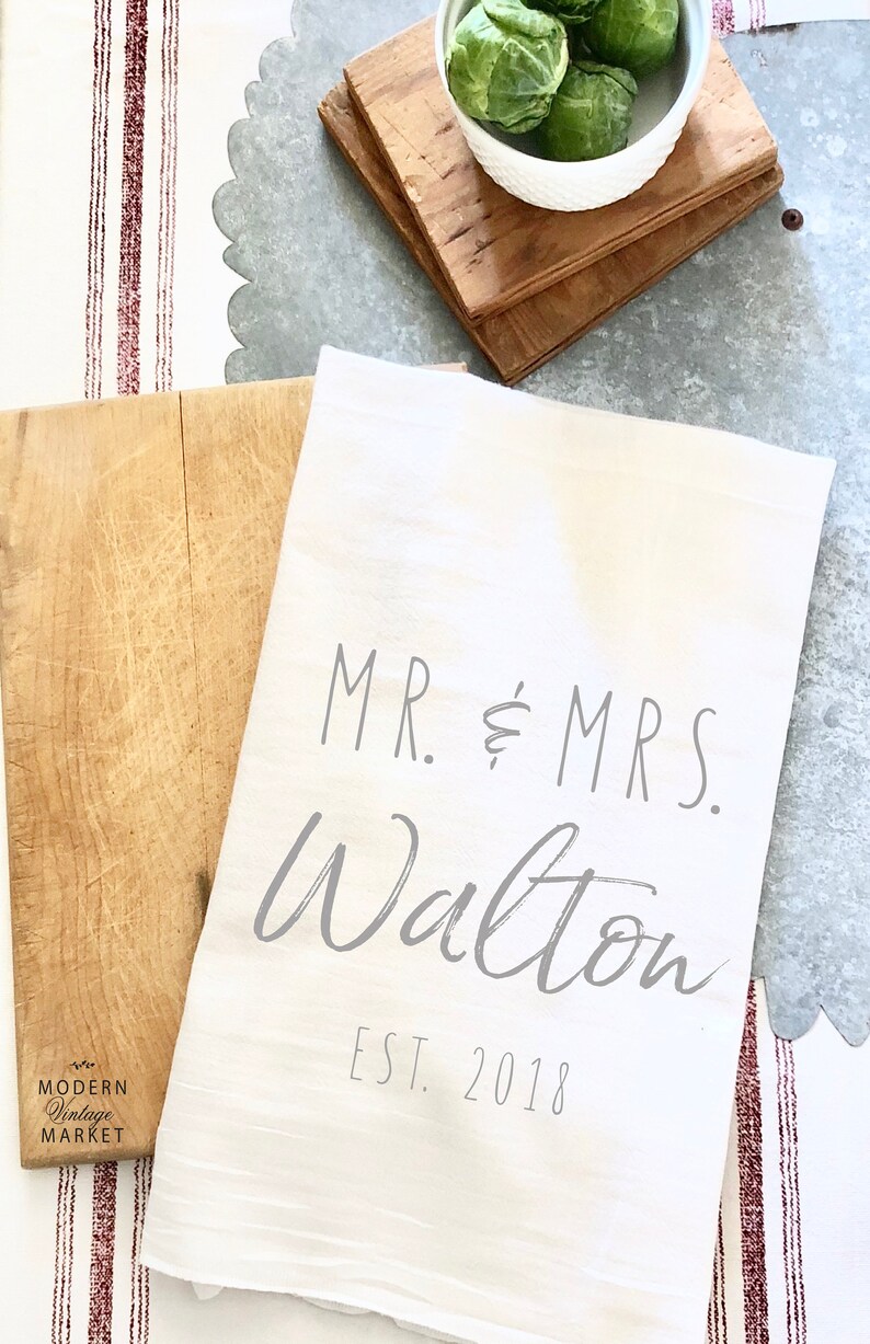 May include: White kitchen towel with the text "MR. & MRS. Walton EST. 2018" printed in gray.