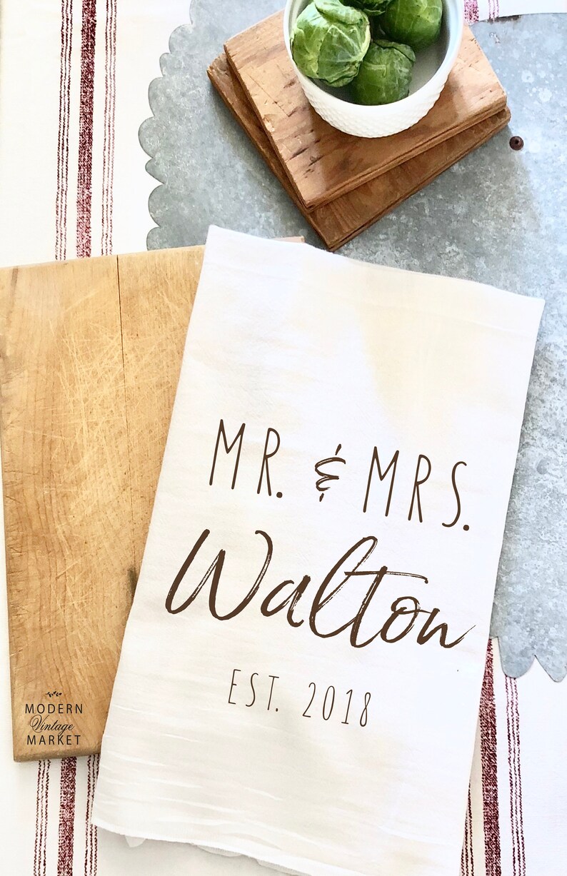 May include: White kitchen towel with the text "MR. & MRS. Walton EST. 2018" in brown lettering.