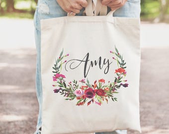 May include: A white canvas tote bag with a floral wreath design and the name "Amy" printed in black script.