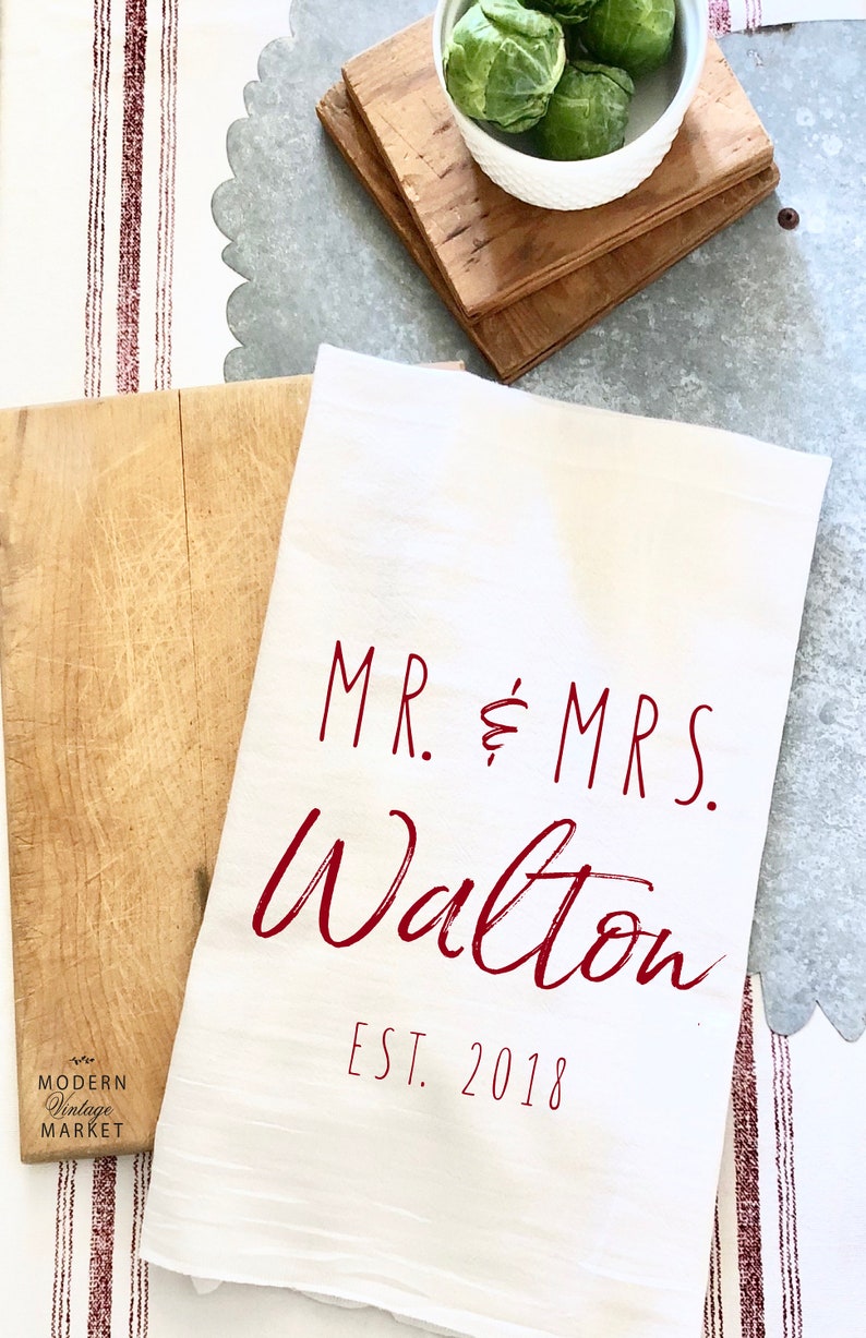 May include: White kitchen towel with the text "MR. & MRS. Walton EST. 2018" in red.