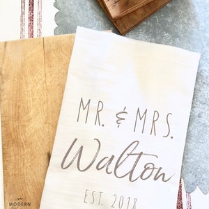May include: White kitchen towel with the text "MR. & MRS. Walton EST. 2018" printed in brown.