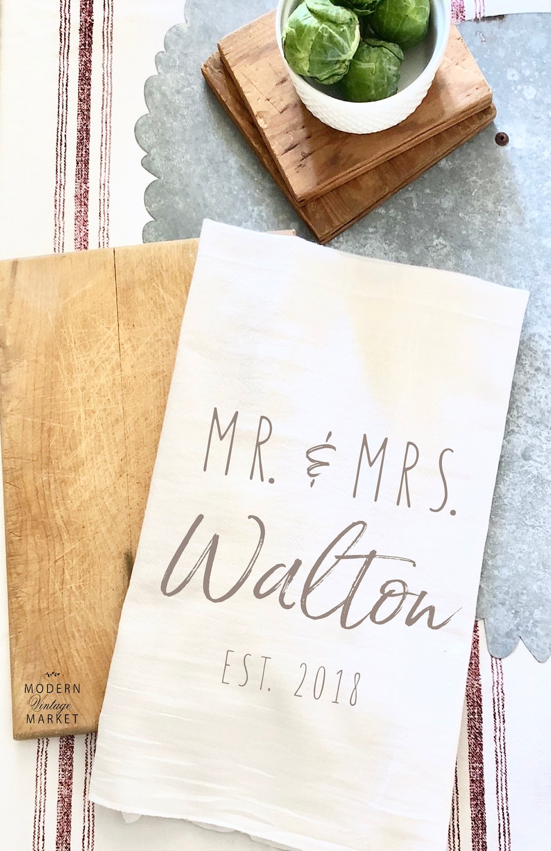 May include: White kitchen towel with the text "MR. & MRS. Walton EST. 2018" printed in brown.