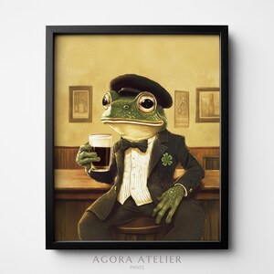 Puede incluir: Impresión enmarcada de una rana elegante con traje y sombrero, sosteniendo una pinta de cerveza oscura. La rana está sentada en un pub, con una pajarita y un trébol de cuatro hojas. Estilo ilustrativo vintage.