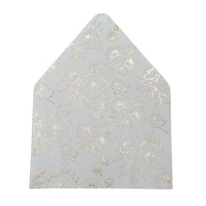 May include: A light gray, triangular-shaped card with a gold floral pattern. The design features detailed gold flowers and leaves, creating a textured appearance. The card's shape is reminiscent of an envelope flap.
