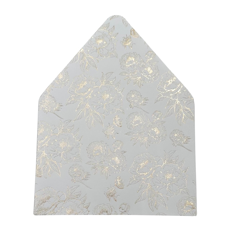 May include: A light gray, triangular-shaped card with a gold floral pattern. The design features detailed gold flowers and leaves, creating a textured appearance. The card's shape is reminiscent of an envelope flap.