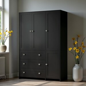 May include: A large, black wooden wardrobe with multiple doors and drawers. The wardrobe has crystal-like knobs and is set against a neutral wall. Yellow flowers in a white vase are on the right, and a vase of yellow flowers is on the left.